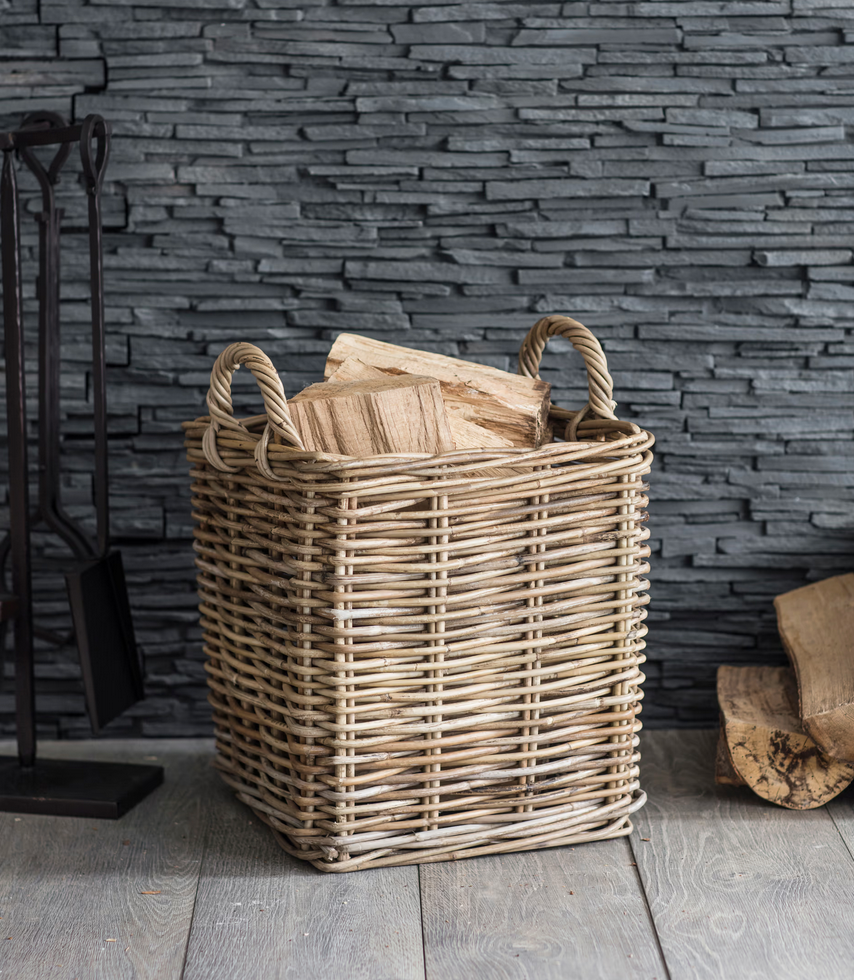 Wicker basket with firewood against a stone wall