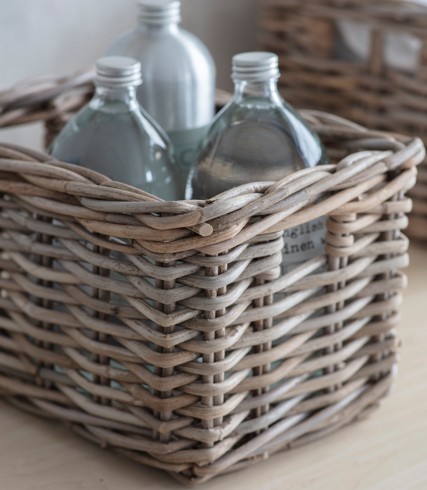 Wicker basket with glass bottles on a light surface