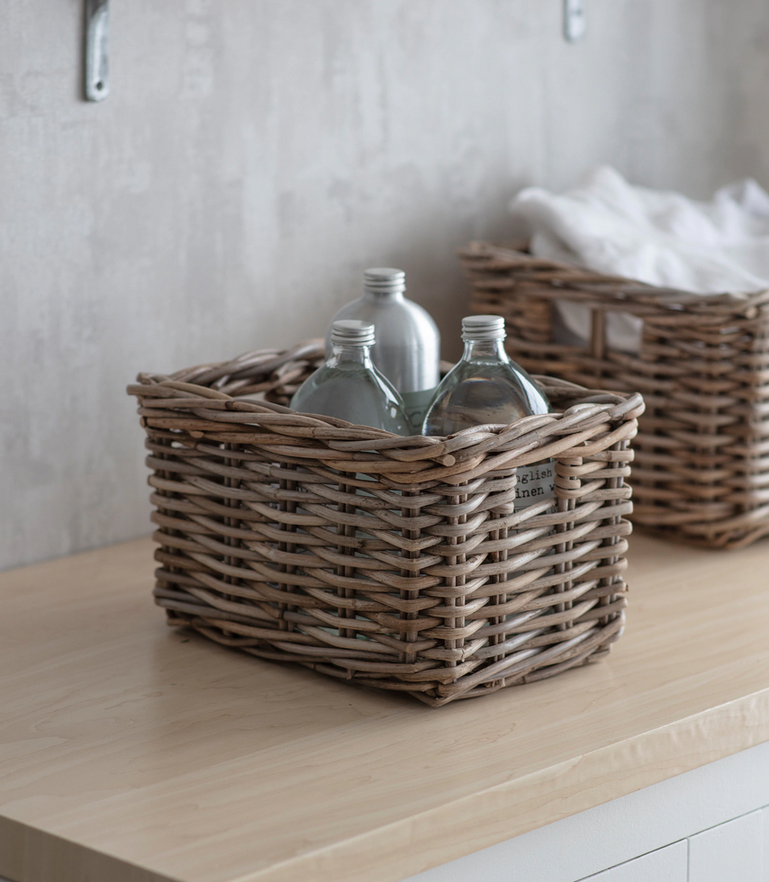 Wicker baskets with bottles on a wooden surface against a neutral wall.