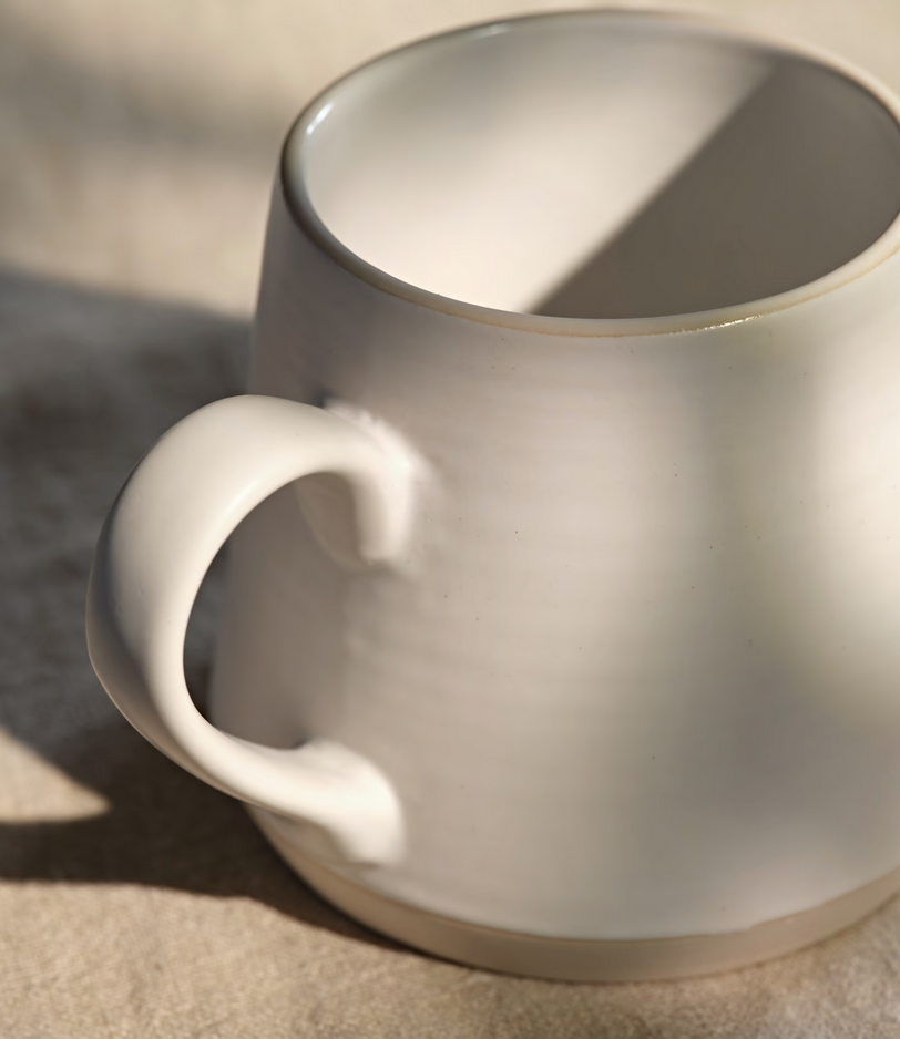 White ceramic mug on a textured surface with soft shadows