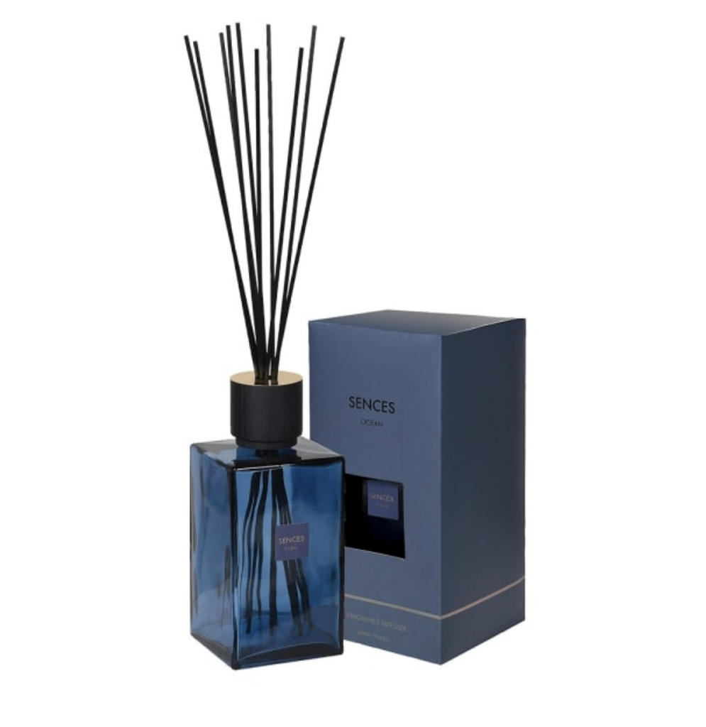 Blue diffuser bottle with black sticks and matching box on a white background