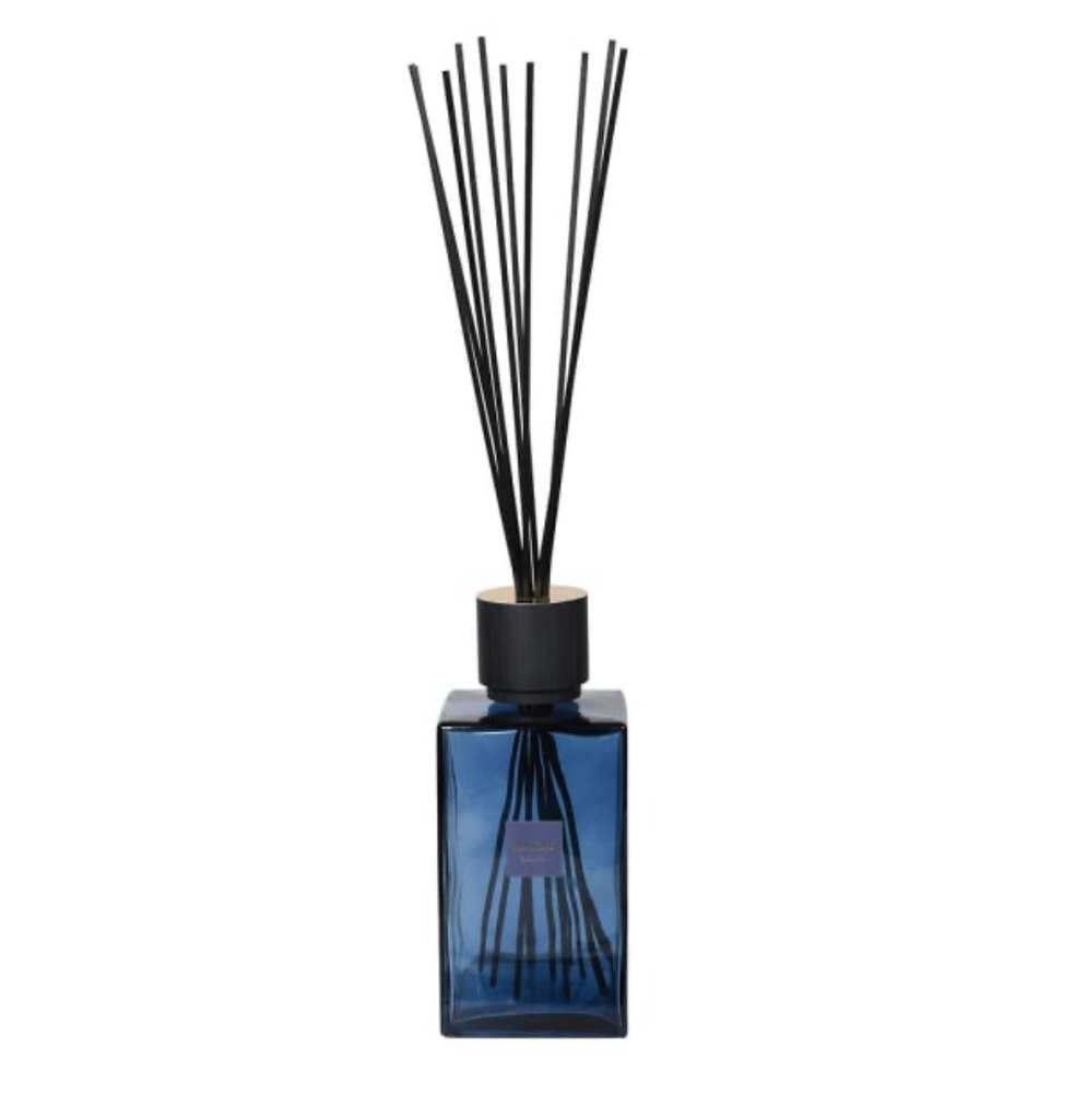 Blue diffuser bottle with black reeds on a white background