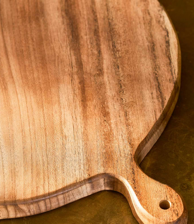 Wooden cutting board with handle on a dark surface