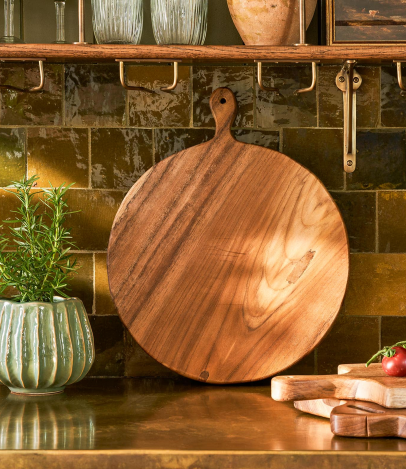 Wooden cutting board on a kitchen counter with a tiled wall in the background